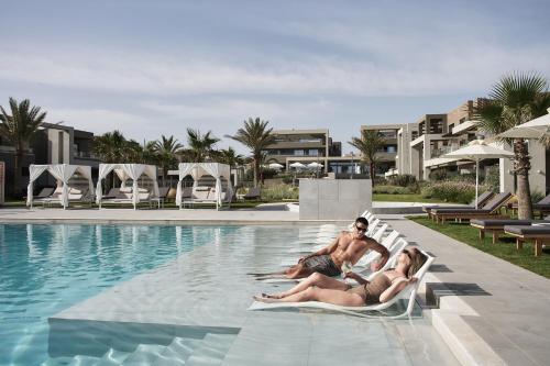 a man and woman sitting in chairs by a swimming pool at Myrion Beach Resort & Spa - Adults Only in Gerani Chanion