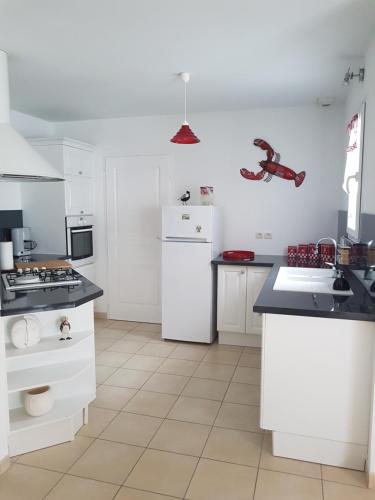une cuisine avec des armoires blanches et un réfrigérateur blanc dans l'établissement Maison de Maud et Julien, à Saint-Pierre-dʼOléron