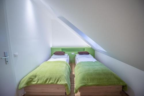 two beds in a attic room with green sheets at Hotel Restaurant Meyer in Kalsdorf bei Graz