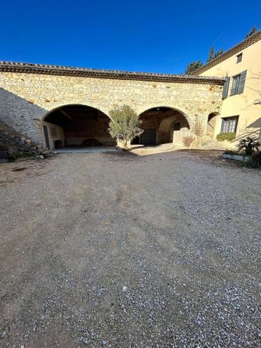 un bâtiment en pierre avec deux arches et un arbre à l'avant dans l'établissement Gite le Sagnac 10 personnes, à Sauzet