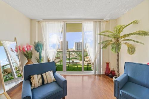 a living room with two blue chairs and a large window at Stunning Water Views 1BR Condo with Pool and Tennis Court in Sunny Isles Beach