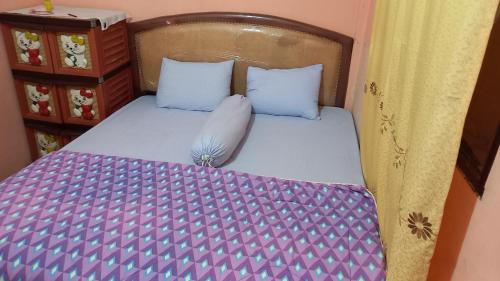a bedroom with a bed with purple and white sheets at Toba Breeze in Pangururan