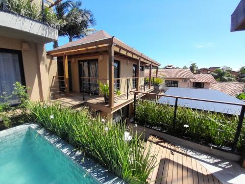 a house with a deck and a swimming pool at Pousada Kirana in Praia do Rosa