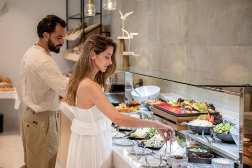 a man and a woman standing in a kitchen preparing food at Myrion Beach Resort & Spa - Adults Only in Gerani Chanion