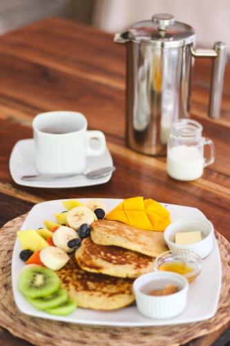 a plate of food with pancakes and fruit and a cup of coffee at VerdeAmar Eco Lodge Jungle Retreat in Chemuyil