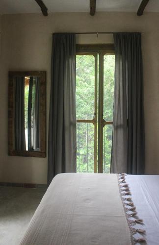a bedroom with a bed and a large window at VerdeAmar Eco Lodge Jungle Retreat in Chemuyil
