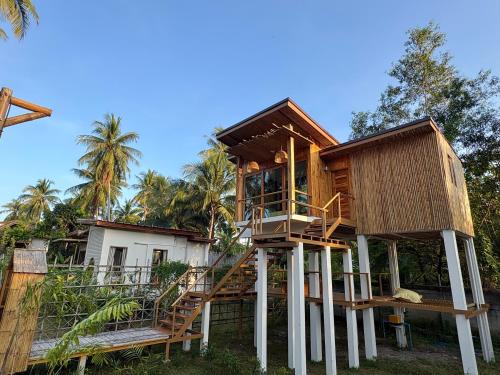 a tree house on stilts in front of a house at บ้านพราวพร้าว Baan Proud Proud in Khanom