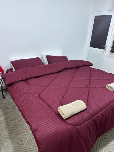 a bed with a purple comforter and two towels on it at Petra candles studios in Petra