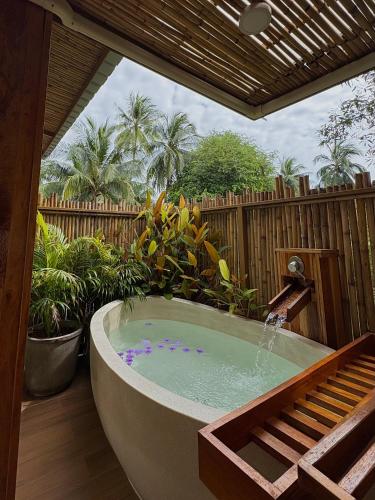 a bath tub in a backyard with a wooden fence at บ้านพราวพร้าว Baan Proud Proud in Khanom