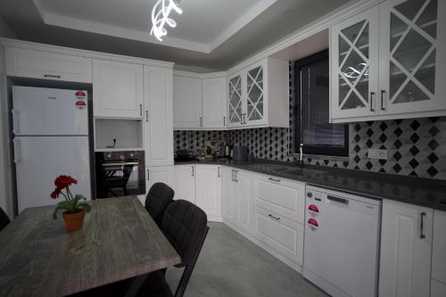 Una cocina con gabinetes blancos y una mesa de madera. en MSD Konakları, en Muğla
