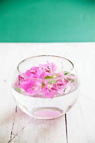 a glass bowl filled with pink flowers on a table at The Beach House in Kep