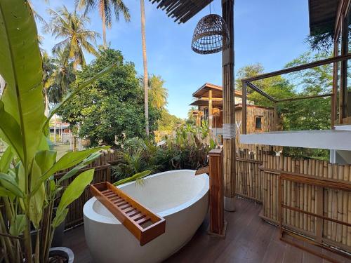 a bath tub sitting on a deck with plants at บ้านพราวพร้าว Baan Proud Proud in Khanom