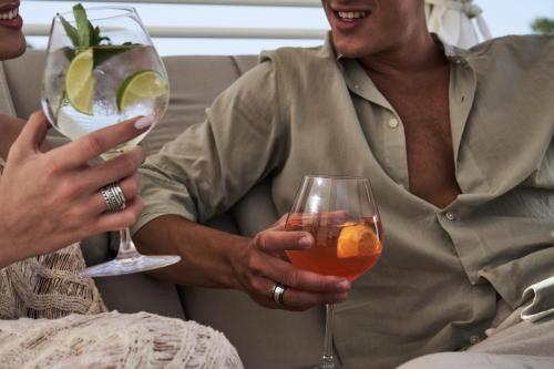a man sitting on a couch holding two wine glasses at Myrion Beach Resort & Spa - Adults Only in Gerani Chanion