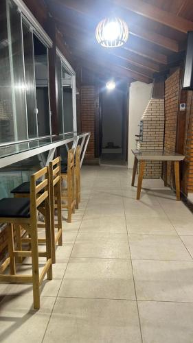 a row of wooden tables and chairs in a room at Casa 3 quartos com Piscina no centro de Penha - SC in Penha