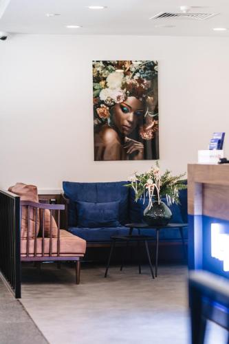 a living room with a blue couch and a painting at Kepler Club Riga Airport Hotel - Landside Public Area in Rīga