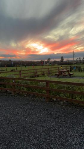 a wooden fence with a picnic table in a field at Emlagh, Self Catering Glamping Pods in Kilkee