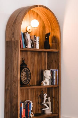 a wooden book shelf with a clock and books at Kepler Club Riga Airport Hotel - Landside Public Area in Rīga