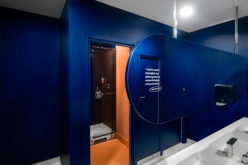 a bathroom with a blue wall and a sink at Kepler Club Riga Airport Hotel - Landside Public Area in Rīga