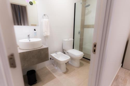 a white bathroom with a toilet and a sink at Departamentos nuevos, excelente ubicación en el centro de Salta in Salta