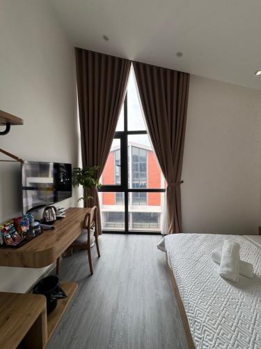 a bedroom with a desk and a bed and a large window at Hayden Home Ocean Park 3 in Ðình Loan