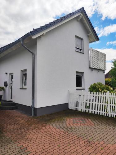 a white house with a fence and a brick driveway at Ferienhaus Glücklich am Harz in Goslar