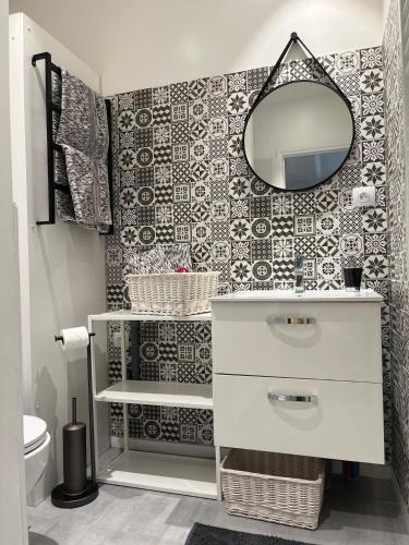 une salle de bain avec un lavabo et un miroir sur un mur dans l'établissement Appartement en centre ville, à Montluçon