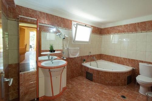 y baño con lavabo, bañera y aseo. en Ilios Hotel & Villas, en Yénion