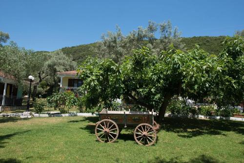 a wooden cart sitting in the grass under a tree at Ilios Hotel & Villas in Yenion