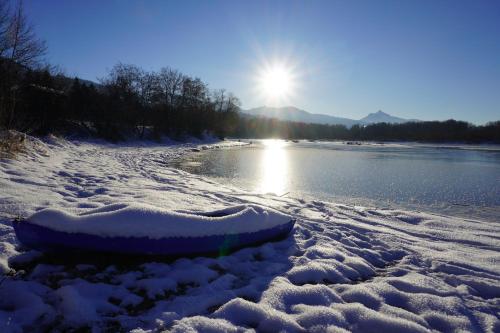 a boat is covered in snow next to a river at FeWo BergZeit auf 1000 m Höhe mit Balkon, Parkplatz, WLAN, Küche in Wertach