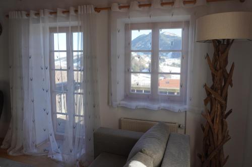 a living room with two windows and a couch at FeWo BergZeit auf 1000 m Höhe mit Balkon, Parkplatz, WLAN, Küche in Wertach
