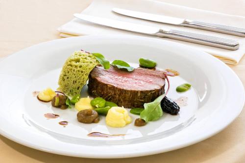 a plate of food with a piece of meat on it at Le Meridien Lav Split in Podstrana