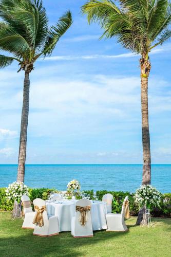 a table and chairs on the beach with palm trees at Sheraton Hua Hin Resort & Spa in Cha Am