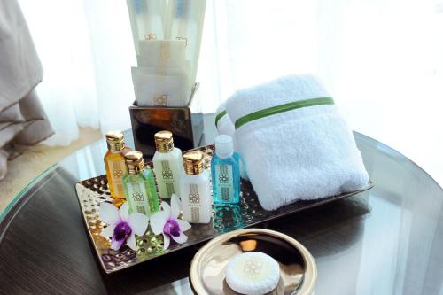 a glass table with a tray of soap and towels at Al Meroz Hotel Bangkok - The Leading Halal Hotel in Bangkok