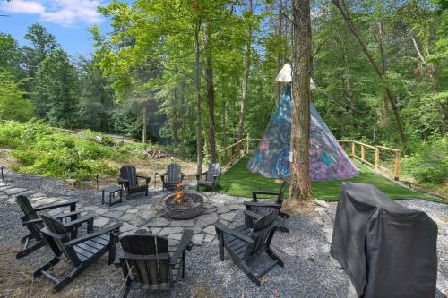 a group of chairs around a fire pit with a tent at Enchanted Forest Cabin And Teepee! Lights & Laser Show! Private Hot Tub! Unique Stay! in Sevierville