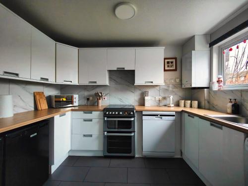 a kitchen with white cabinets and a black oven at Haydon Hill House in Buckinghamshire