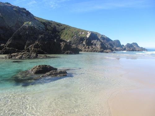 a beach with some rocks in the water at O Lagar in Santa Marta de Ortigueira