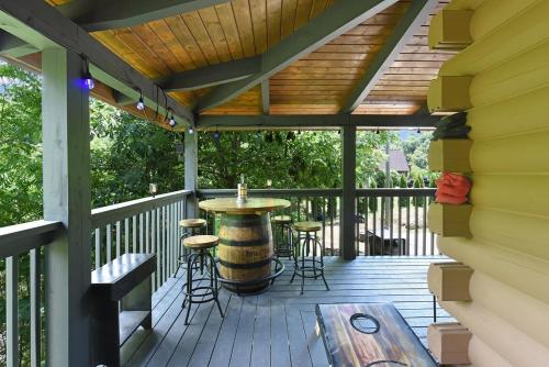 a wooden deck with a barrel table and stools at Ryes and Shine Bootlegger's Cabin! Hot Tub* Pool* Arcade* Billiards *EV * Pet Friendly in Sevierville