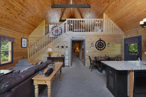a living room with a staircase in a wooden cabin at Ryes and Shine Bootlegger's Cabin! Hot Tub* Pool* Arcade* Billiards *EV * Pet Friendly in Sevierville