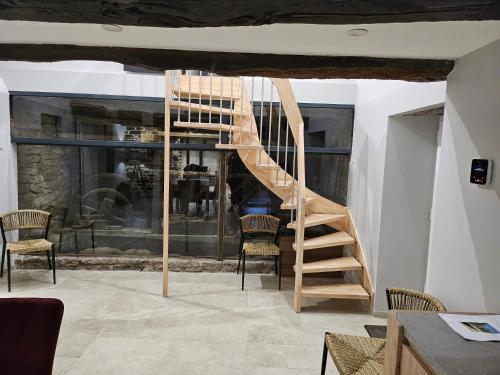 a wooden spiral staircase in a room with chairs at Moulin de Kerstrat in Brennilis