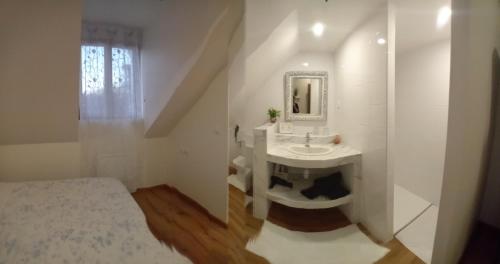 a white bathroom with a sink and a mirror at Le Moulin des Roses in Neslette