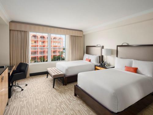 a hotel room with two beds and a desk at Hamilton Princess & Beach Club A Fairmont Managed Hotel in Hamilton