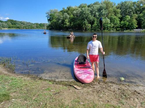 a man standing next to a pink kayak in the water at Pintyőke Vendégház Tőserdő in Lakitelek