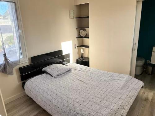 - une chambre avec un lit doté d'une couverture blanche et d'une fenêtre dans l'établissement Bugle, à Saumur