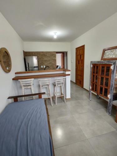 a kitchen with a counter and stools in a room at Casas no Centro Histórico de Garopaba in Garopaba