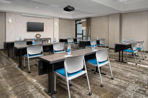 a conference room with tables and chairs and a screen at SpringHill Suites by Marriott Atlanta Perimeter Center in Atlanta