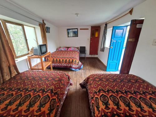 a room with two beds and a blue door at Las Portadas in Ollantaytambo