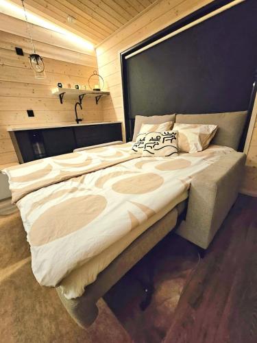 a large bed in a room with a wooden wall at Beach cottage with sauna in Kajaani