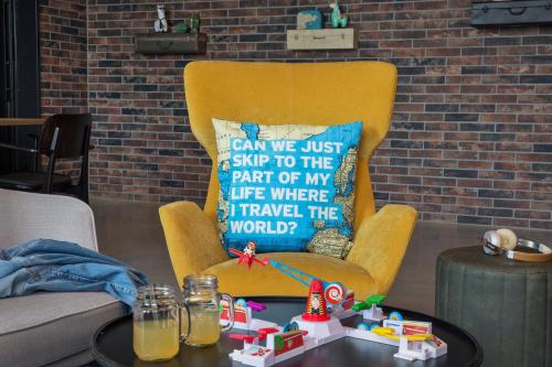 a yellow chair in a living room with a table at Moxy Frankfurt Airport Kelsterbach in Kelsterbach