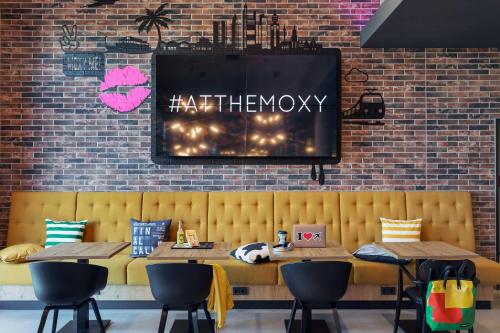 a restaurant with a yellow bench and a brick wall at Moxy Frankfurt Airport Kelsterbach in Kelsterbach