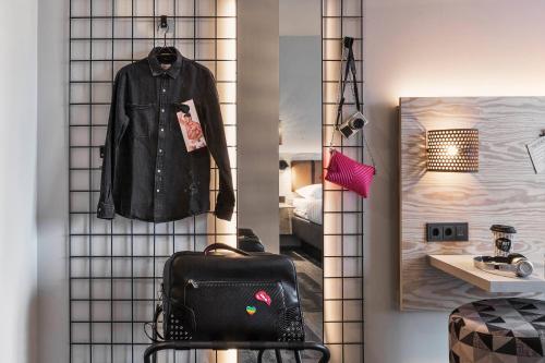 a black jacket hanging on a wall with a bag at Moxy Frankfurt Airport Kelsterbach in Kelsterbach